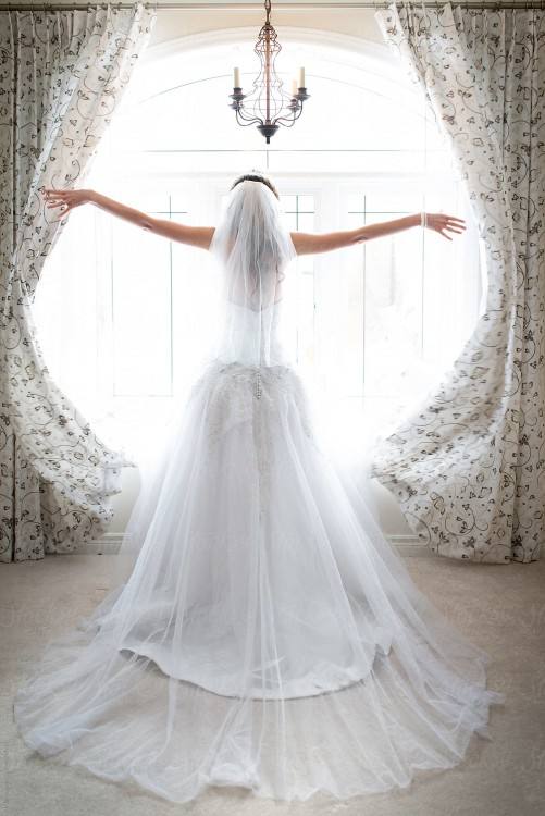Wedding dress hanging in a window, taken vertically in monochrome, black  and white