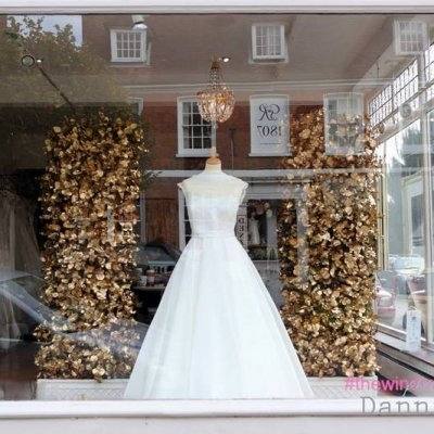 Beautiful bride hanging fashion white wedding dress on a hanger near window  in hotel room